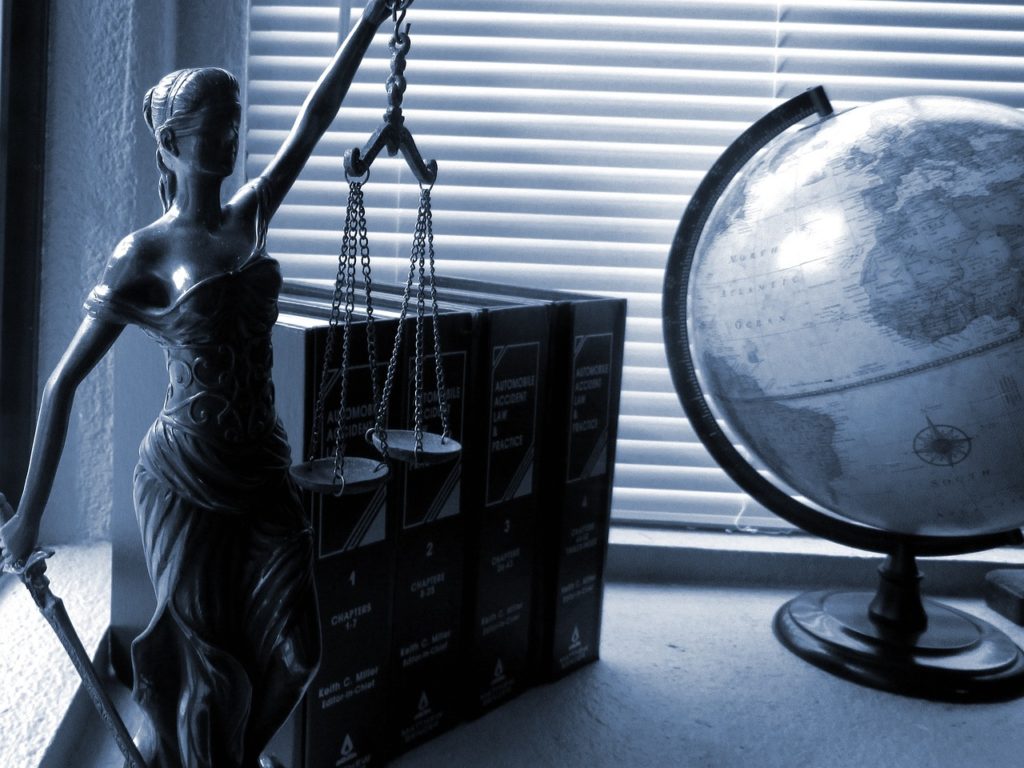 Imagen de la diosa justicia, un globo terráqueo y unos libros de leyes jurídicas.