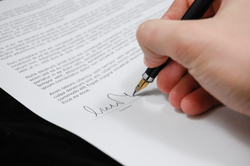 Imagen persona firmando contrato con una pluma